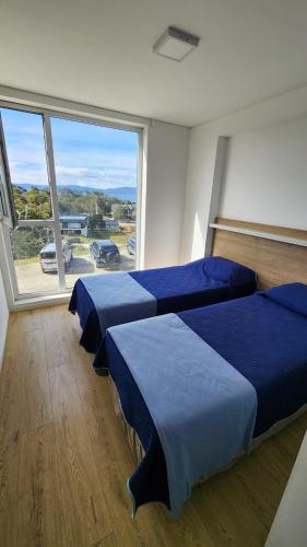 two beds in a room with a large window at Terrazas del Beagle Deluxe in Ushuaia