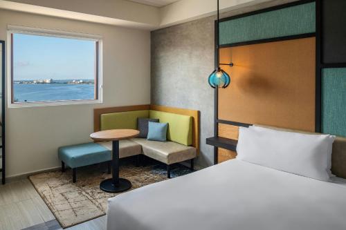 a hotel room with a bed and a table and a window at Aloft Cancun in Cancún