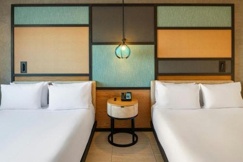 two beds in a room with a table between them at Aloft Cancun in Cancún