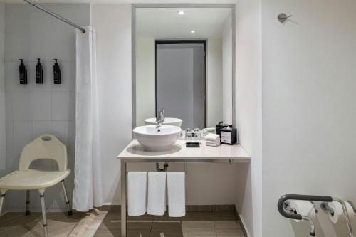 a white bathroom with a sink and a mirror at Aloft Cancun in Cancún