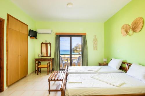 a bedroom with two beds and a view of the ocean at Sun Beach Apartments in Karpathos Town
