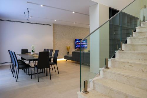 a dining room with a table and chairs and a staircase at SanPietro Premium Villas in Draçi