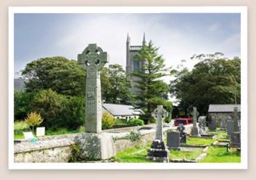 a cemetery with a cross and a church in the background at Yeats Lodge in Drumcliff