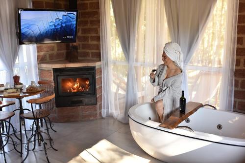 ベント・ゴンサルベスにあるCabana com lareira, hidro, cavalos e piscinaの女性が暖炉のある部屋のバスタブに座っている