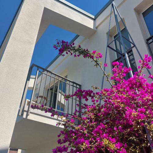 a white house with purple flowers and a balcony at Slowersilia Bed and Breakfast in Lido di Camaiore