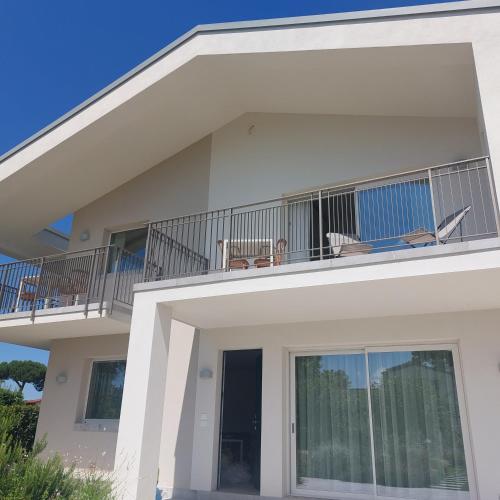 a white house with two chairs and a balcony at Slowersilia Bed and Breakfast in Lido di Camaiore
