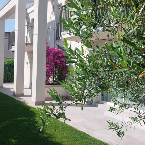 a white building with pink flowers in a yard at Slowersilia Bed and Breakfast in Lido di Camaiore