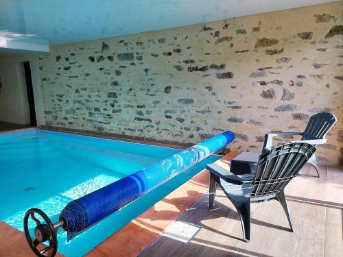 - une piscine avec un tube bleu dans une pièce avec des chaises dans l'établissement La Villa du Cap - indoor pool - billiards table, à Fouesnant