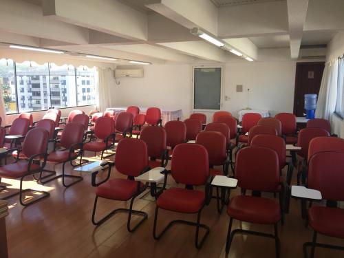 a room with red chairs and desks in a classroom at Colle Tourist Hotel Standard Sem Elevador in Criciúma