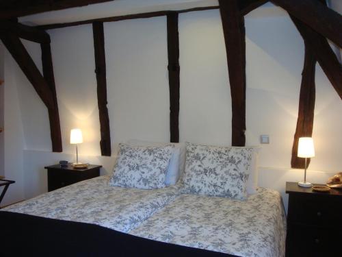une chambre avec un lit avec des oreillers et deux lampes dans l'établissement Beaulieu Apartments, à Beaulieu-sur-Dordogne