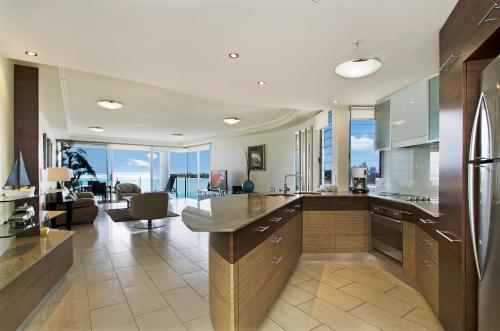 a kitchen with wooden cabinets and a living room at Waves Maroochy River in Maroochydore