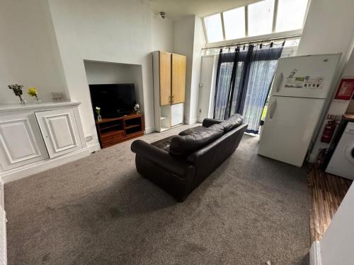 a living room with a black leather couch and a refrigerator at Double-Bedroom in the Heart of Salford Manchester GCSW6 Perfect for Short Stays in Manchester