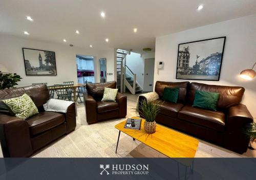 a living room with brown leather couches and a table at Ironbridge Home with Roof Terrace in Ironbridge