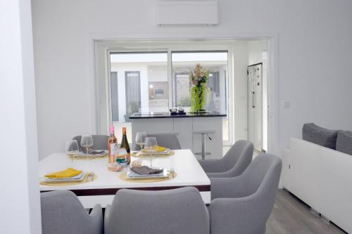 a dining room with a white table and chairs at Ruhiges Modernes Haus Parkplatz WLAN Whirlpool in Aveiro