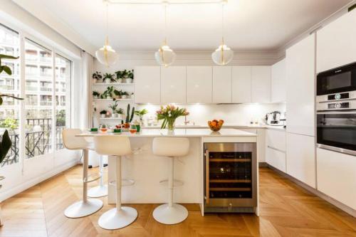 une cuisine avec des placards blancs et un îlot avec des tabourets de bar dans l'établissement Maison Josephine Stunning Apartment Champs-Elysees 3 bedrooms, à Paris