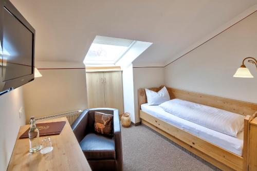 a room with a bed and a desk and a television at Landgasthof Zur Post in Schwangau