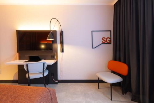 a room with a bed and a desk and two chairs at Holiday Inn - the niu, Blade Solingen by IHG in Solingen