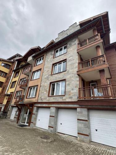 a large building with four garage doors in front of it at Pirin Golf View Apartment Bansko in Bansko