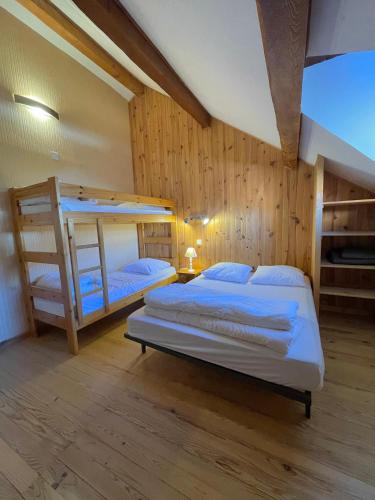 DUPLEX CENTRE RISOUL 1850 في ريسول: سريران بطابقين في غرفة ذات جدران خشبية