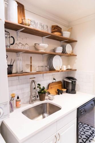 a kitchen with a sink and shelves with dishes at Charming and Historic Apartment in Capitol Hill in Washington, D.C.