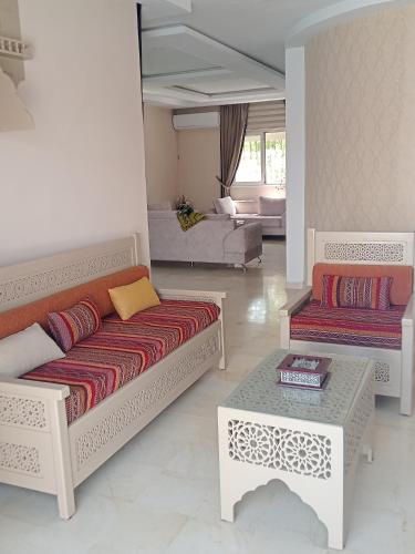 a living room with two couches and a table at Villa lucky in Hammamet