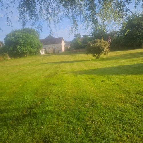 un grand champ d'herbe verte avec un bâtiment en arrière-plan dans l'établissement Les Hirondelles, à Chemiré-en-Charnie