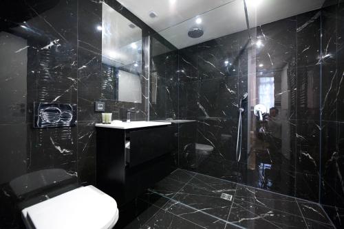 La salle de bains noire est pourvue d'une douche et de toilettes. dans l'établissement CIA - Vosges Gem, à Paris