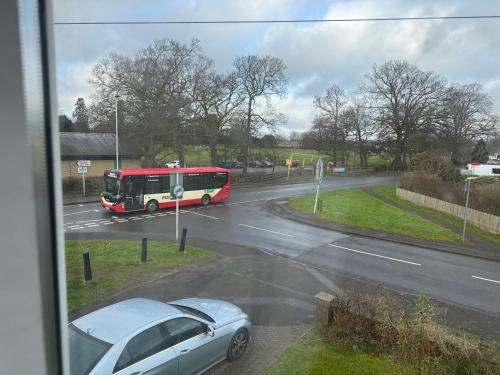 a red and white bus driving down a street with a car at Modern Studio Appartment in Cheltenham