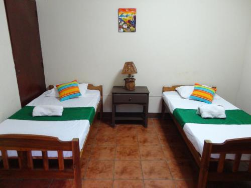 duas camas individuais num quarto com mesa de cabeceira em Hostal El Jardin em León