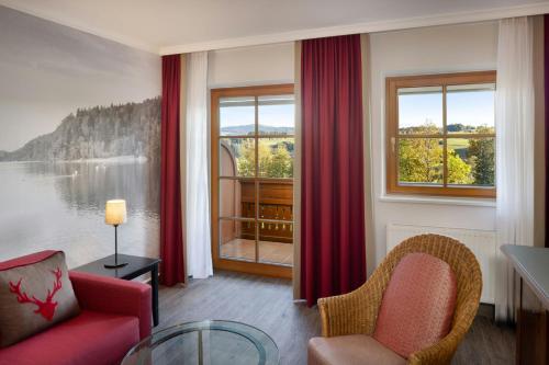 a living room with a red couch and a window at Arabella Jagdhof Resort am Fuschlsee, a Tribute Portfolio Hotel in Hof bei Salzburg