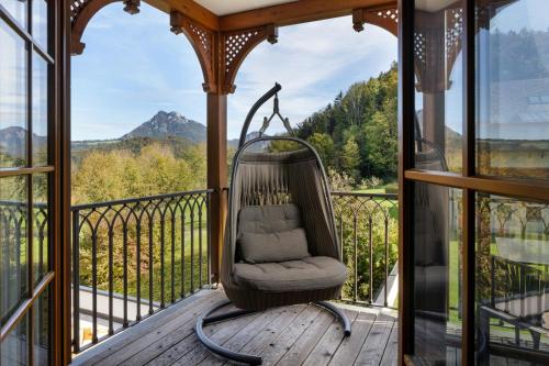 a chair on a porch with a view of a mountain at Arabella Jagdhof Resort am Fuschlsee, a Tribute Portfolio Hotel in Hof bei Salzburg