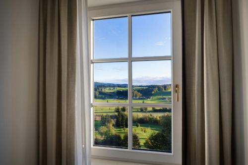 a window with a view of a green field at Arabella Jagdhof Resort am Fuschlsee, a Tribute Portfolio Hotel in Hof bei Salzburg
