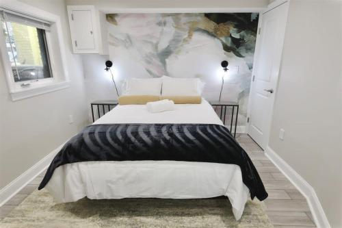 a white bedroom with a large bed with black and white sheets at Darling Apartment in Capitol Hill - TWO min to Metro in Washington, D.C.