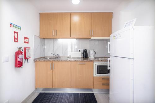 a kitchen with wooden cabinets and a white refrigerator at Bay View by OCvillas in Albufeira