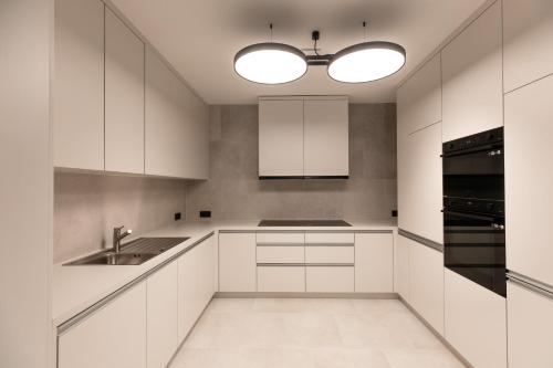 a white kitchen with white cabinets and a sink at Henry's Appt with a private Suite 412 - Shared kitchen in Luxembourg