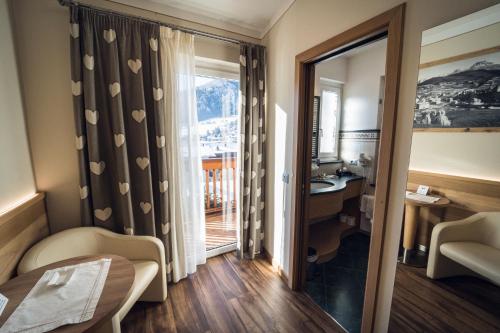 a hotel room with a desk and a window at Hotel Alle Alpi in Moena
