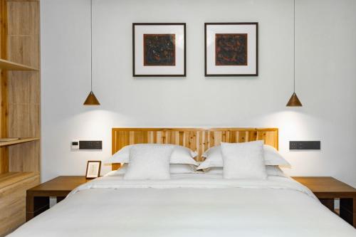 a bedroom with a large bed with white sheets at Standing in the wild in Xiwu