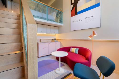 a living room with a red chair and a table at The Rebyl, Nijmegen, a Tribute Portfolio Hotel in Nijmegen
