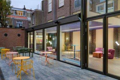 a patio with tables and chairs and windows at The Rebyl, Nijmegen, a Tribute Portfolio Hotel in Nijmegen