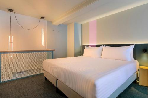 a bedroom with a large bed with white sheets at The Rebyl, Nijmegen, a Tribute Portfolio Hotel in Nijmegen