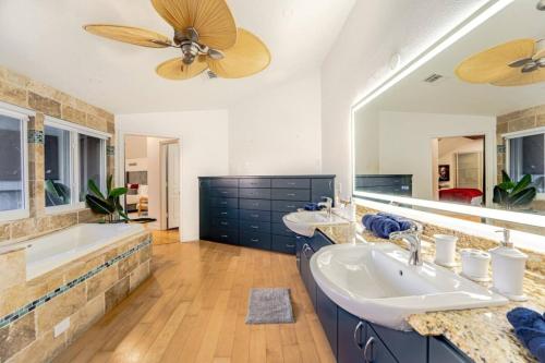 une salle de bain avec deux lavabos et un grand miroir dans l'établissement Beachfront Oasis w Htd Pool Cinema Game-Room Tiki, à Pompano Beach