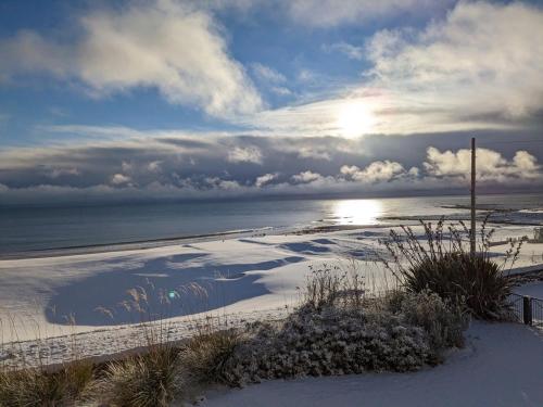 a beach with snow on it and the ocean at No10 The Links Apartment, Brora in Brora