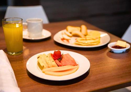 een tafel met borden en een glas sinaasappelsap bij Betania Hotel in Santa Marta