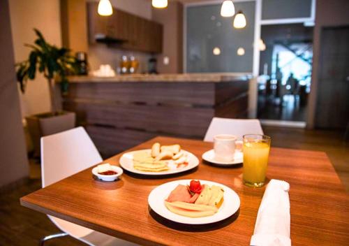 een houten tafel met twee borden eten en sinaasappelsap bij Betania Hotel in Santa Marta