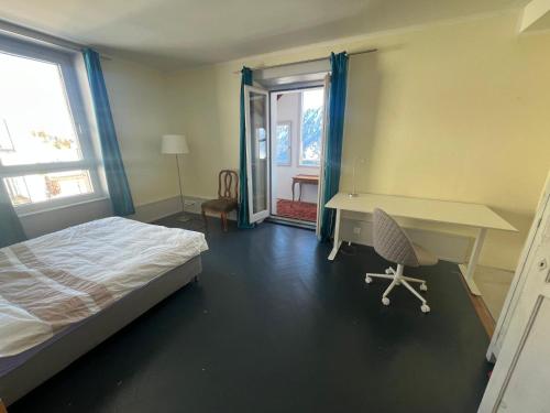 a bedroom with a bed and a desk and window at Belle Maison au cœur des alpes in Leysin