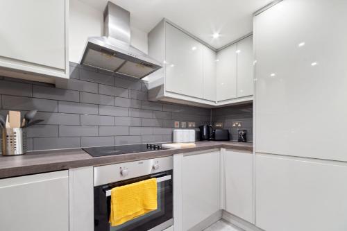 a kitchen with white cabinets and a yellow towel at City Centre Gem - Apartment Sleeps 5 in Leicester