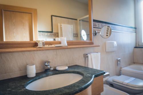 a bathroom with a sink and a toilet and a mirror at Hotel Alle Alpi in Moena