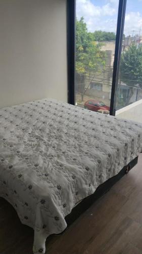 een bed in een kamer met een groot raam bij Hermoso Monoambiente lanusita in Lanús