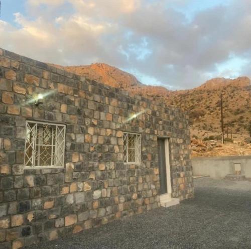 a brick wall with two windows and a door at بيت دار السوداء in Dār Sawdāʼ