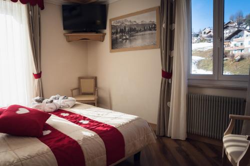 a bedroom with a bed with a television and a window at Hotel Alle Alpi in Moena